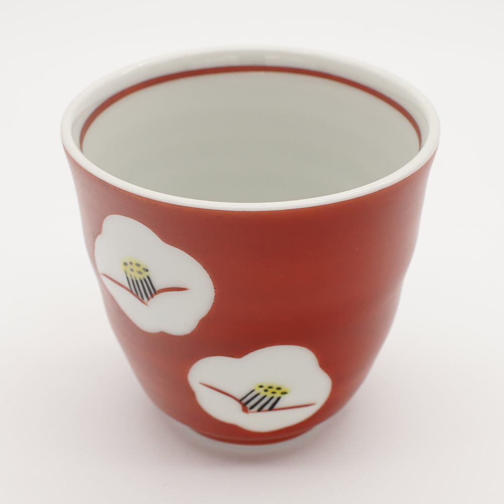 Ruby red tea cup with two delicate white camellia flower designs, showcasing exquisite Japanese ceramic craftsmanship