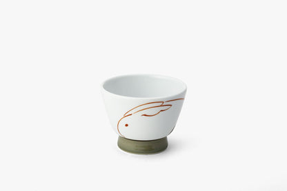 Elegant white porcelain wine cup with minimalist terracotta sakura-rabbit design and muted green base, showcasing modern Japanese artistry