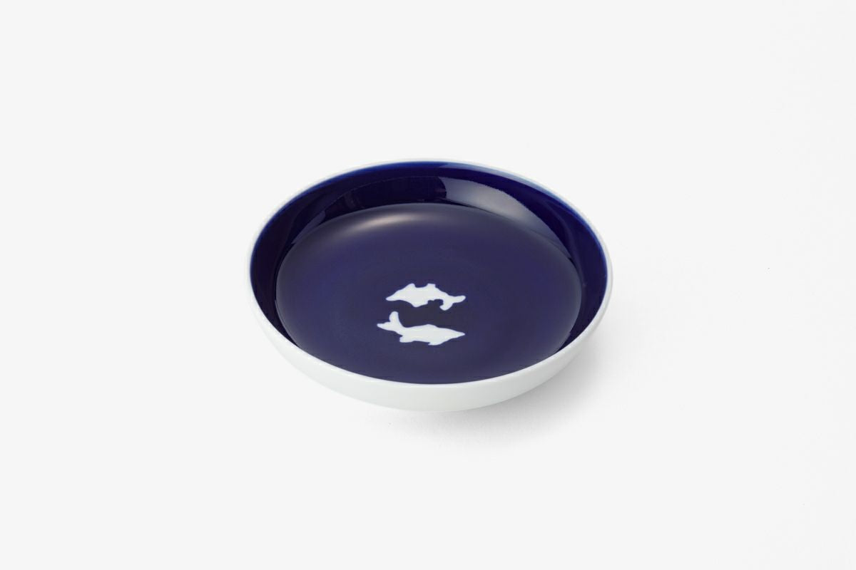 Deep blue ceramic plate with white twin fish design, showcasing Ming dynasty techniques and Japanese aesthetic principles