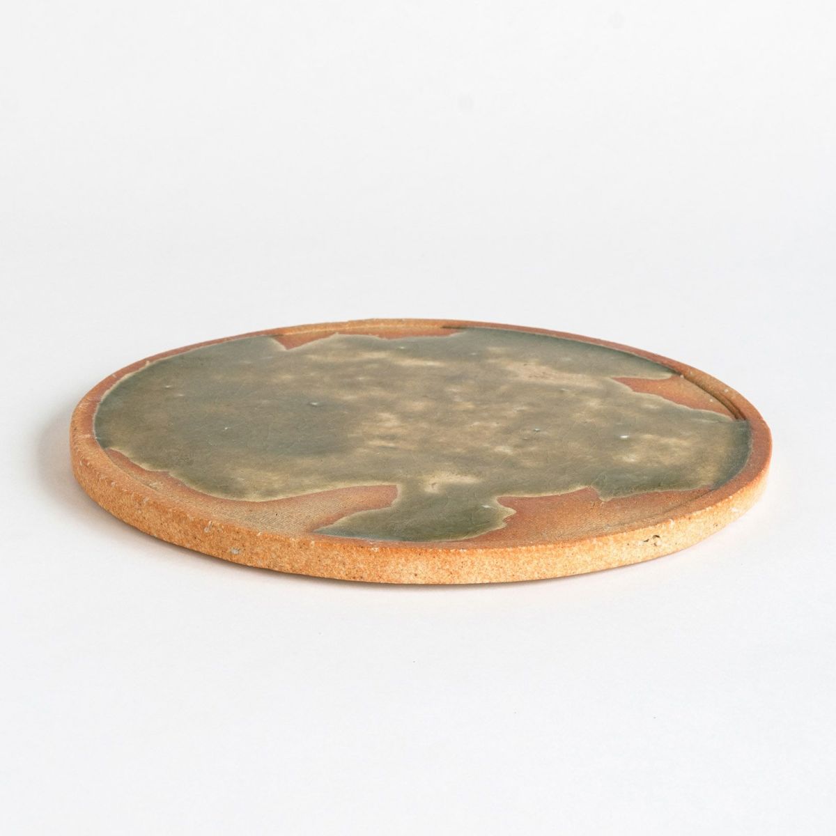 Handcrafted large Koshinraku round ceramic plate with green glazed center and natural clay rim, showcasing traditional Japanese pottery techniques