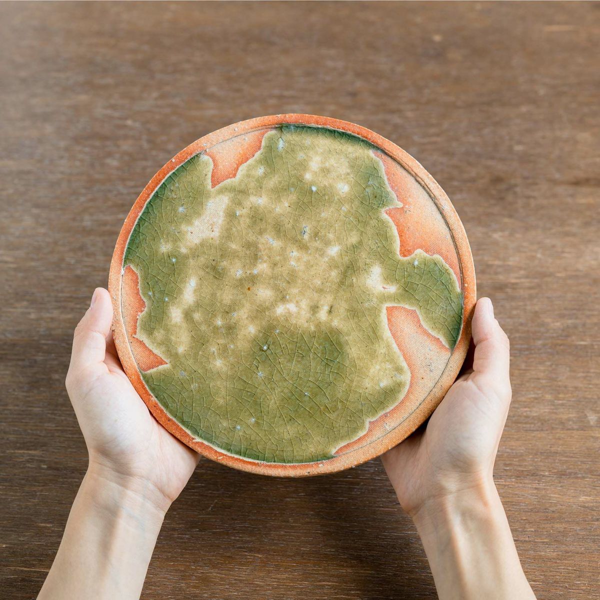 Handcrafted large Koshinraku round ceramic plate with green glazed center and natural clay rim, showcasing traditional Japanese pottery techniques