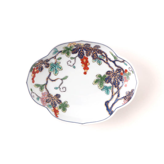 Handcrafted Japanese oval plate featuring intricate grapevine design with purple leaves, red grapes, and green accents on a white background with scalloped edges