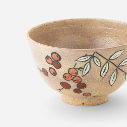 Handcrafted Japanese tea bowl with nanten berry design, featuring delicate red berries and green leaves hand-painted on a warm, earthy base