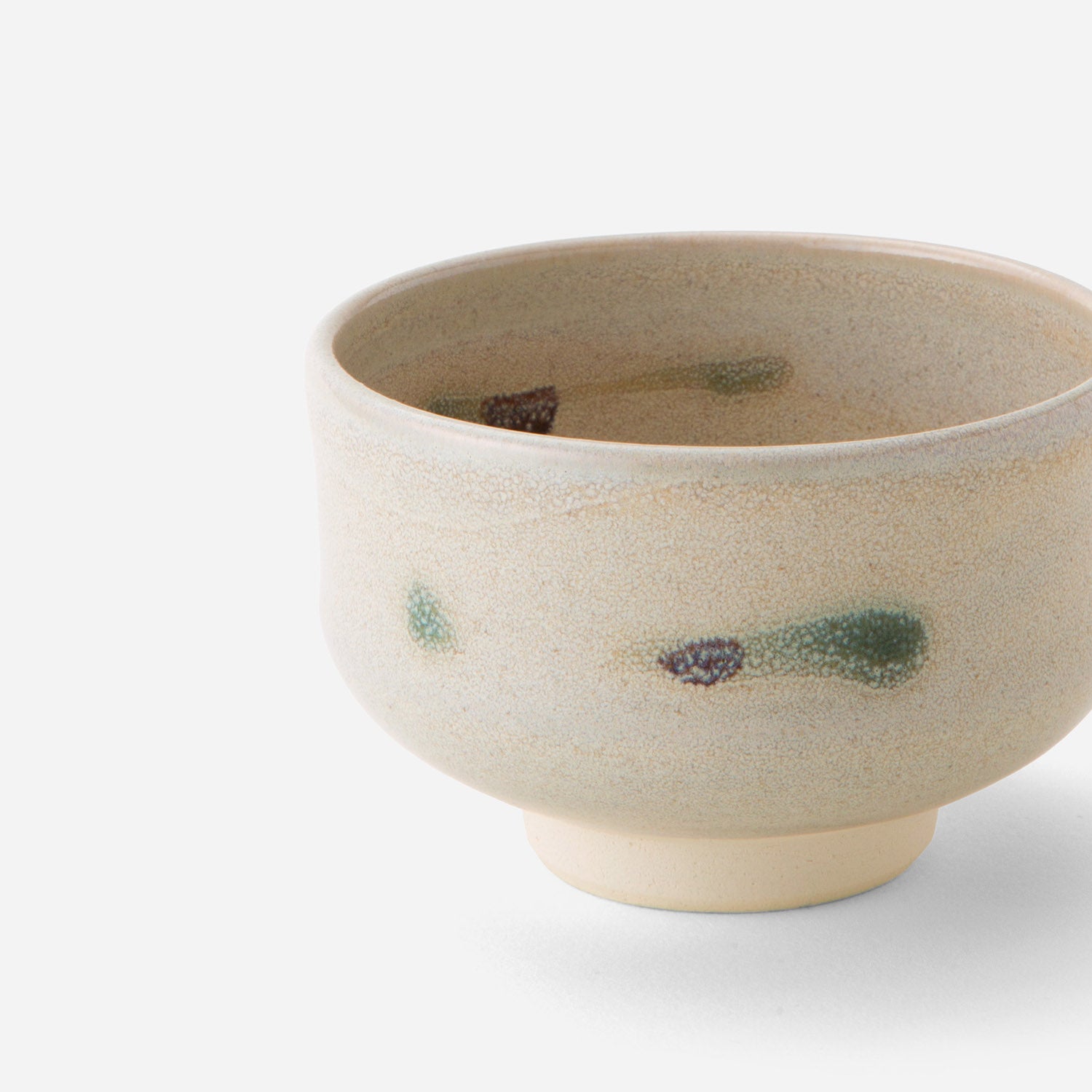 Handcrafted Japanese tea bowl with rustic tricolor glaze, featuring subtle green and brown brushstrokes on a creamy base, embodying wabi-sabi aesthetics