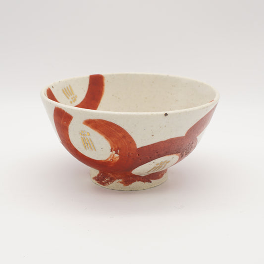 Creamy white rice bowl with bold crimson brushstrokes and gold accents, showcasing modern Japanese ceramic artistry