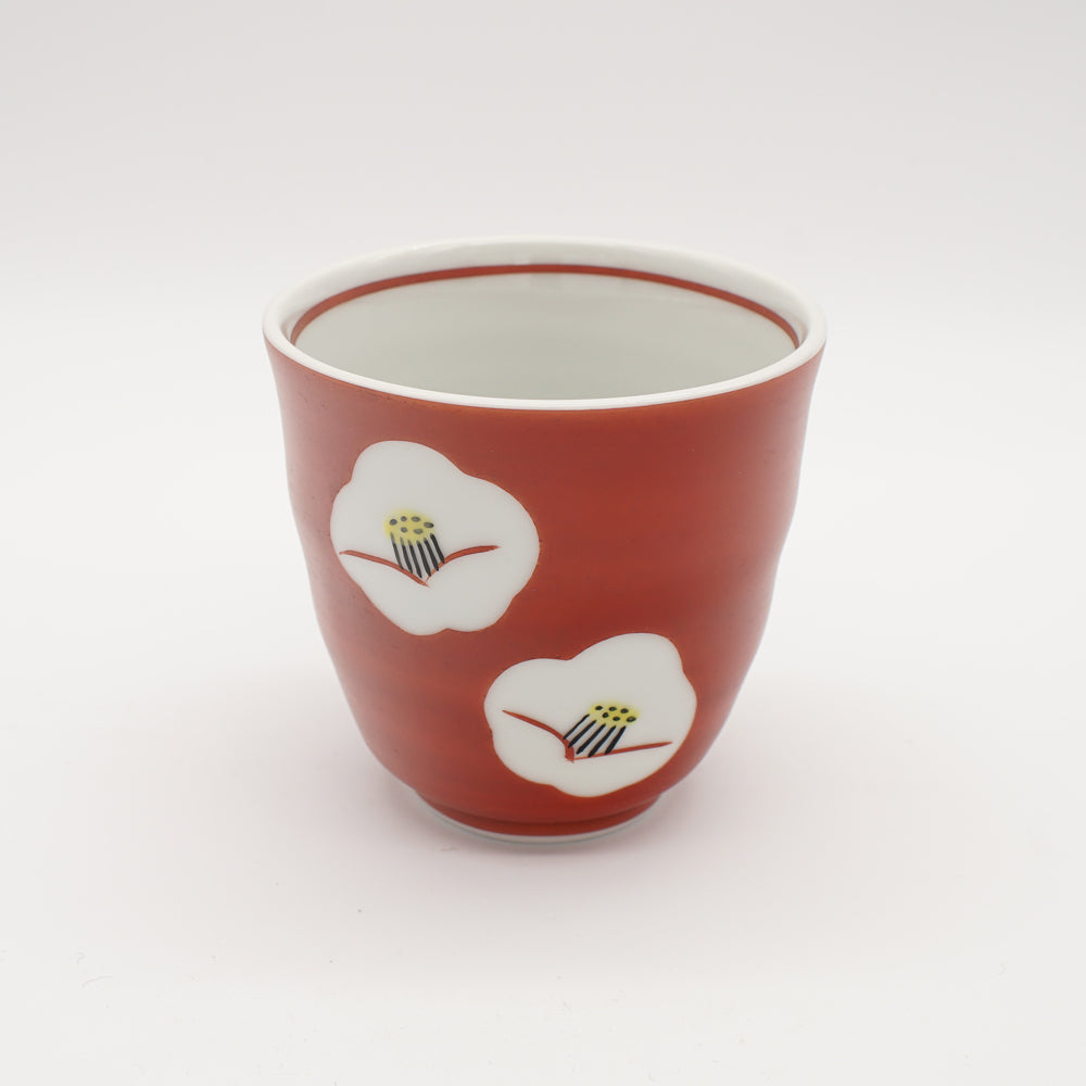 Ruby red tea cup with two delicate white camellia flower designs, showcasing exquisite Japanese ceramic craftsmanship