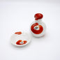 White ceramic soy sauce dispenser with red camellia flower design, accompanied by a matching red saucer for elegant serving