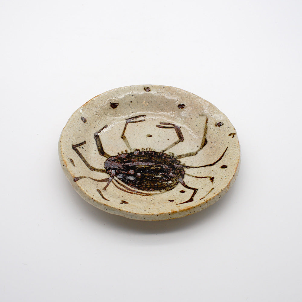 Rustic beige ceramic plate with hand-painted dark brown crab motif, showcasing traditional Japanese pottery techniques and marine-inspired design